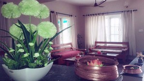A living room with a sofa, a coffee table, a plant, and a copper pot on a table. - Hotel Nana Pokhara (Pokhara)