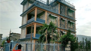 A multi-story building with balconies and a stone base. - Hotel Nana Pokhara (Pokhara)