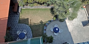 An outdoor patio area with two round tables, each surrounded by four white plastic chairs.
