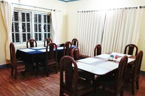 A conference room with a large table and chairs, a window with blinds, and curtains.