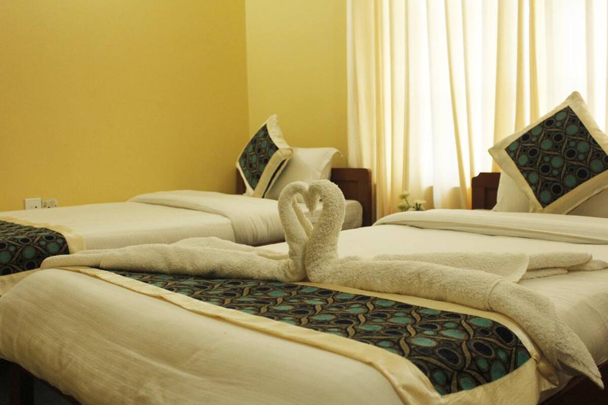Une chambre d’hôtel avec deux lits, chacun étant agrémenté d’une couvre-lit à motifs et de coussins.