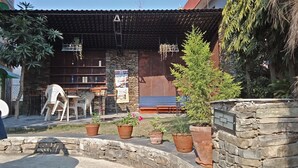 A stone building with a tiled roof, outdoor seating, and potted plants. - Hotel Nana Pokhara (Pokhara)