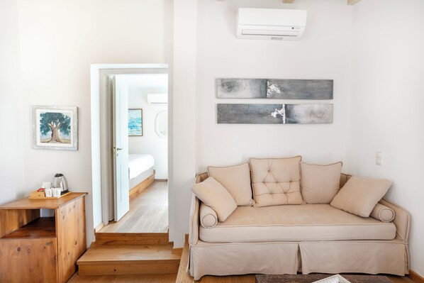 A modern living room with a beige sofa, wooden side table, and artwork on the wall. - Z boutique Hotel (Mylopotamos)
