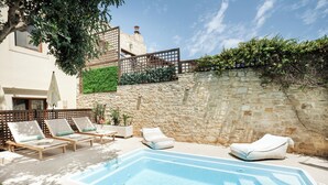 A swimming pool with lounge chairs and a stone wall. - Z boutique Hotel (Mylopotamos)