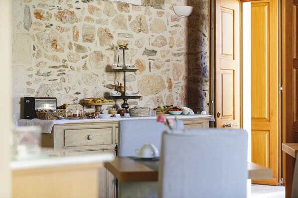 Una cocina rústica con paredes de piedra, armarios de madera y una barra de desayuno con diversos alimentos.