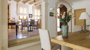 A dining area with a wooden table, chairs, and a vase of flowers. There is a staircase leading to another room. - Z boutique Hotel (Mylopotamos)