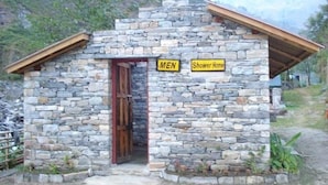 Ein Steinhaus mit einer Holztür und einem Schild, auf dem 'MEN Shower Home' steht.