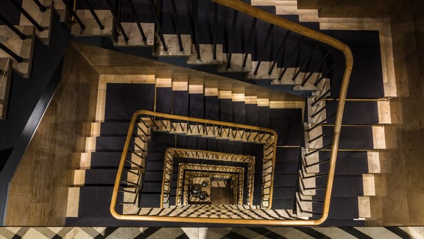 A spiral staircase with a checkered floor pattern and a wooden handrail. - The Midtown Hotel by The New Yorker (Cologne)