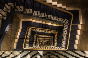 Uma escadaria em espiral com um padrão de piso quadriculado e um corrimão de madeira.