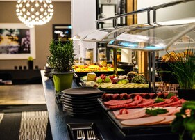 Um buffet com diversos alimentos, incluindo carnes, queijos e frutas.