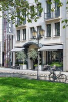 Hotel com fachada moderna, área de estar externa e uma bicicleta estacionada na frente.