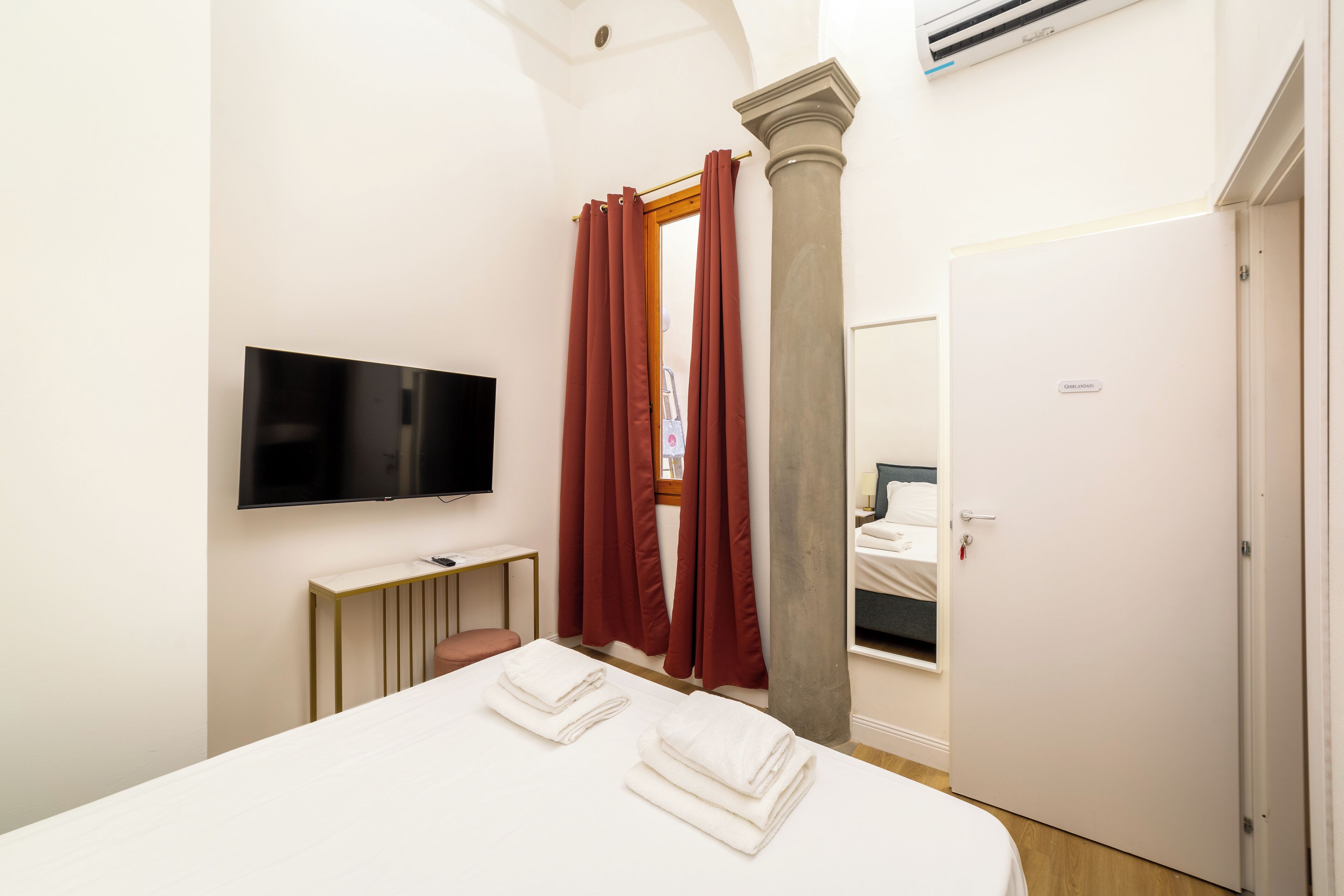 Une chambre d’hôtel équipée d’un lit, d’un téléviseur à écran plat, d’un bureau et d’une porte.