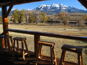 A wooden deck with stools overlooking a mountainous landscape and a body of water. - Paradise Gateway B&B and Vacation Homes (Emigrant)