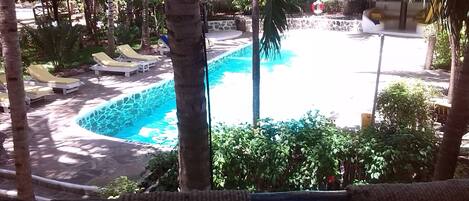 Un espace piscine avec des chaises longues et un mur en pierre.