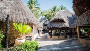 A pathway leading to thatched-roof structures with a sign indicating 'Room 1 from 1 to 3'. - Scorpio Villas Resort (Malindi)