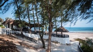 A beachside resort with thatched-roof structures, a sandy walkway, and a view of the ocean. - Scorpio Villas Resort (Malindi)