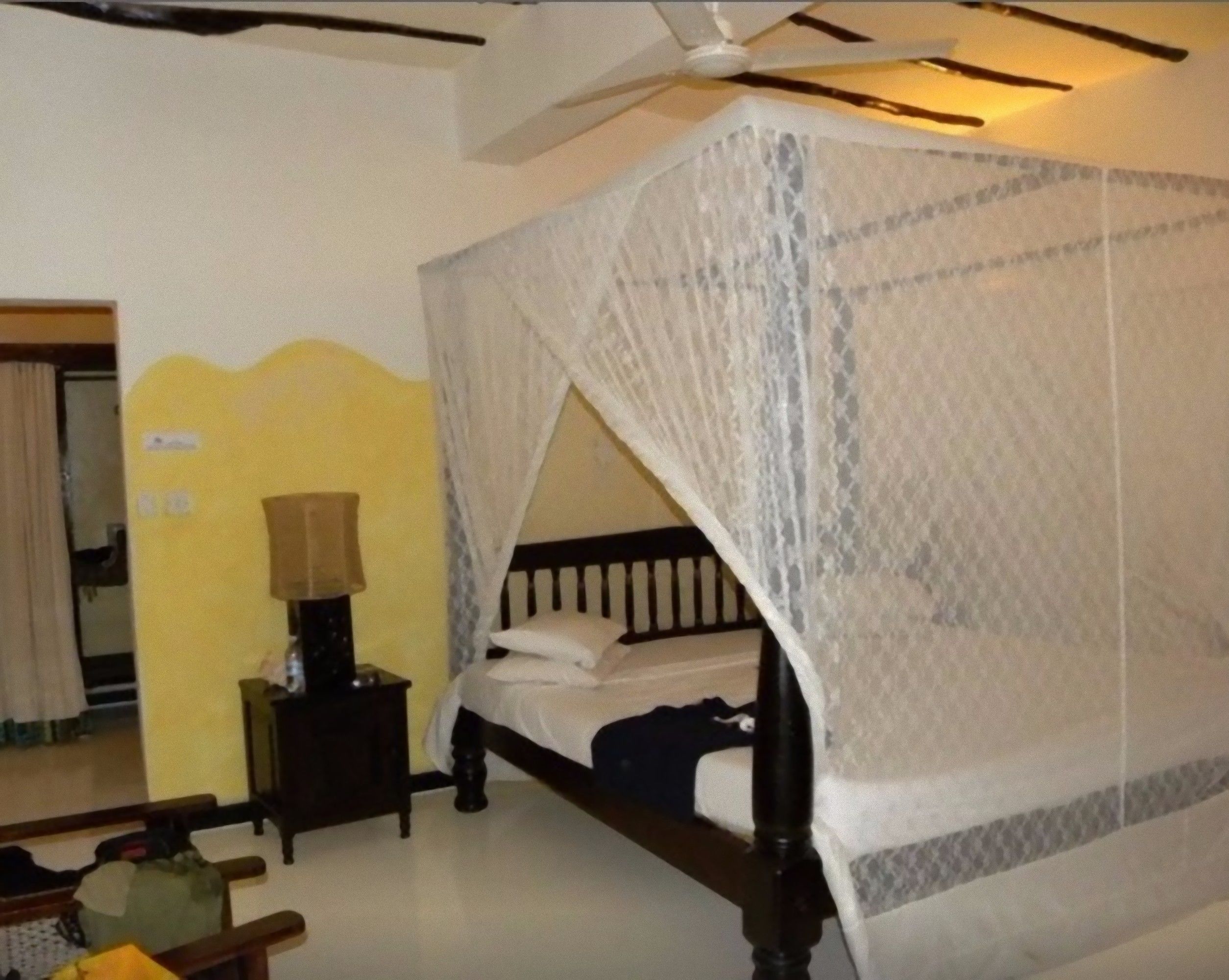 Un dormitorio con una cama con dosel, una mesita de noche y una lámpara.