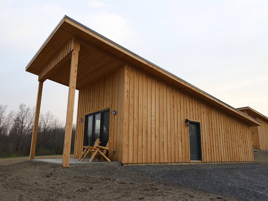 Un bâtiment en bois doté d’un porche couvert, d’une porte portant l’inscription « 37 » et d’une chaise placée à l’extérieur.