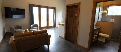 A spacious living room with a sofa, chairs, a television, and a sliding glass door leading to an outdoor area.
