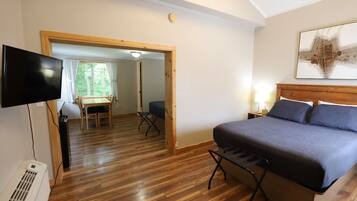 A bedroom with a bed, a TV, and a wooden floor.