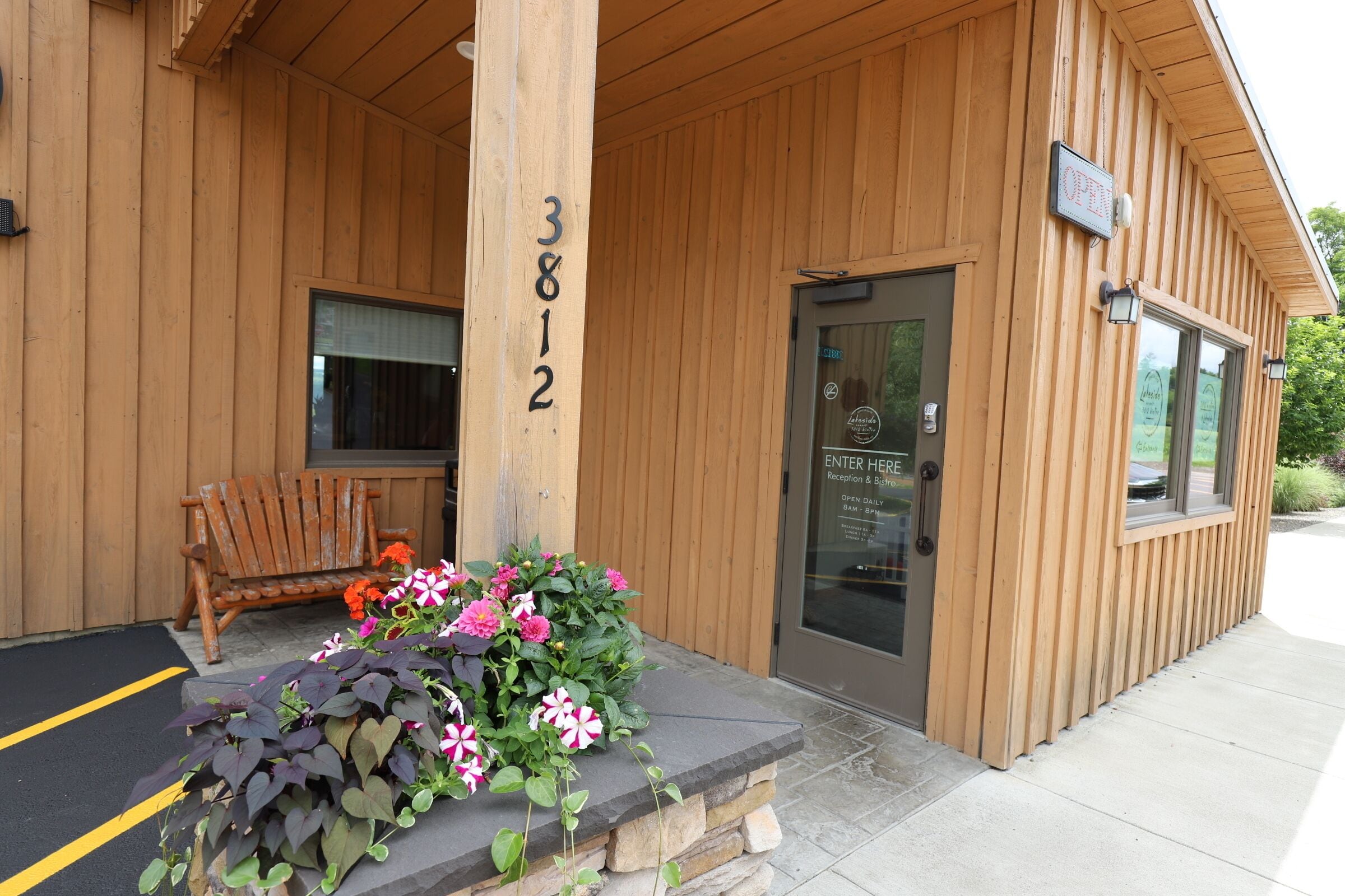 A wooden building with a stone planter with flowers in front.
