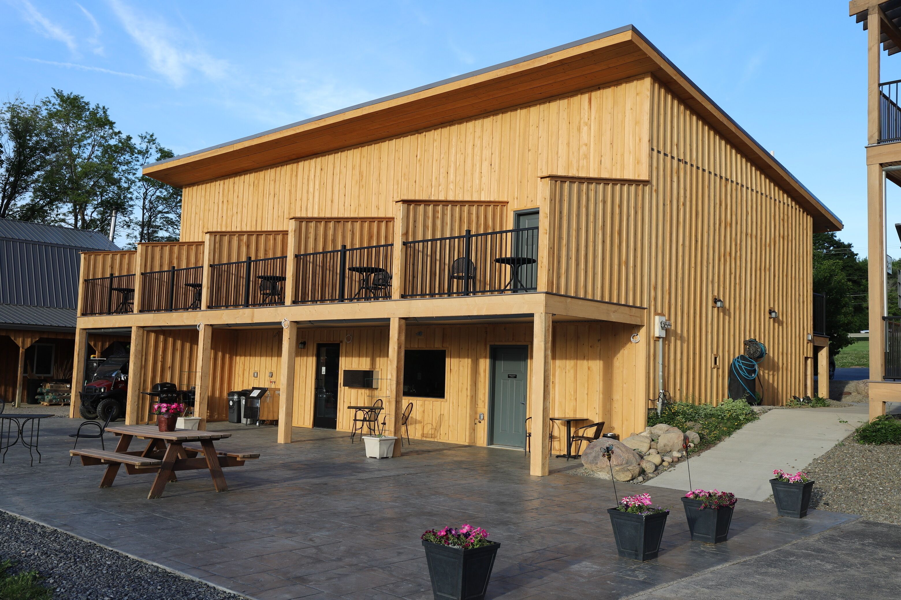 Un edificio de madera con un patio cubierto, mobiliario exterior y una parrilla de barbacoa.