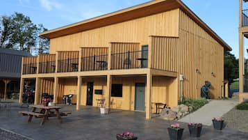 Un edificio de madera con un patio cubierto, mobiliario exterior y una parrilla de barbacoa.