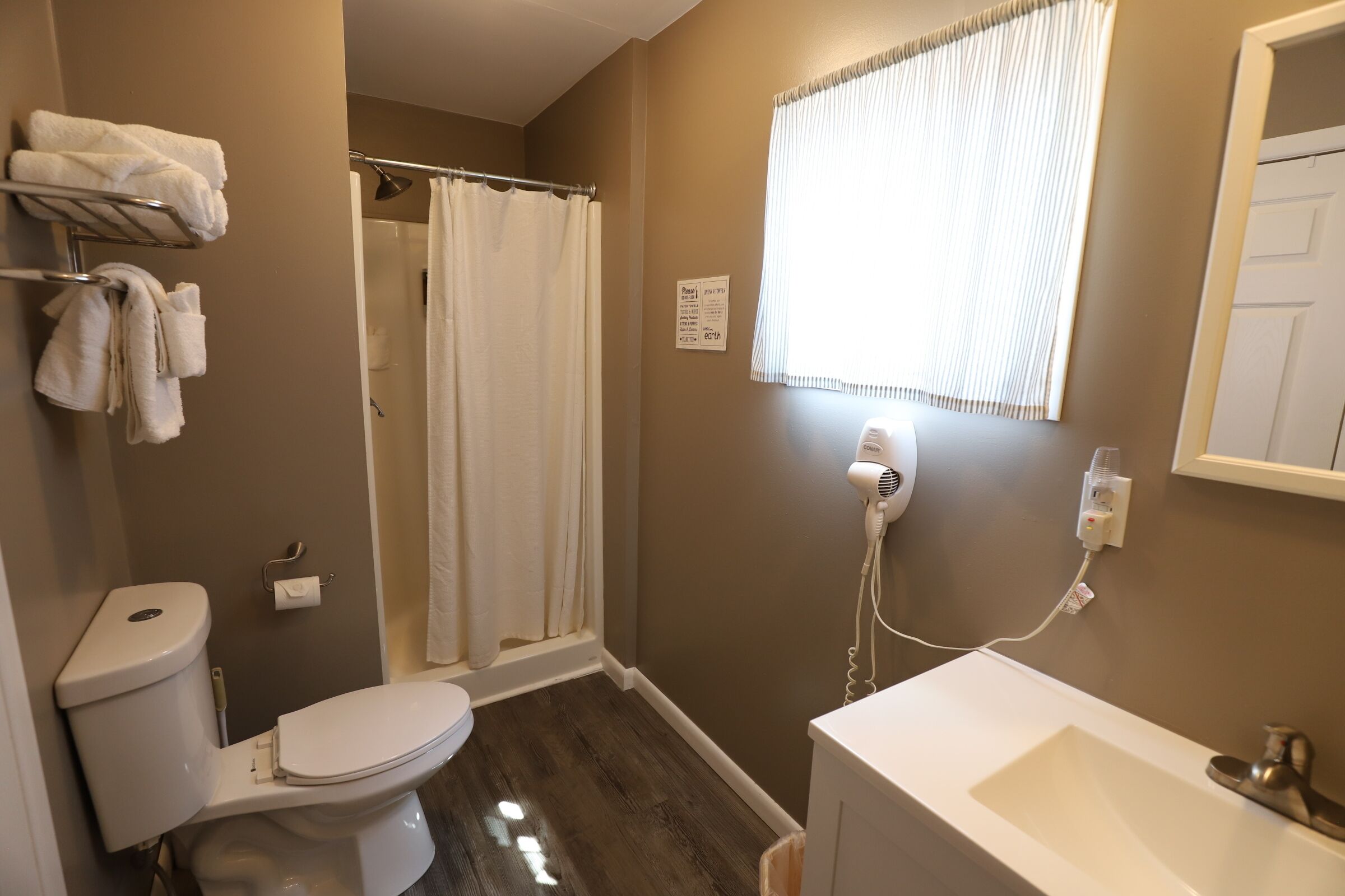 A bathroom with a toilet, a shower curtain, a hairdryer, and a sink.