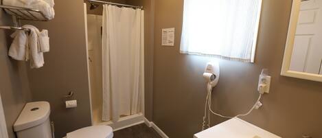 A bathroom with a toilet, a shower curtain, a hairdryer, and a sink.