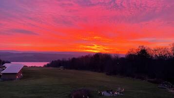 A sunset over a grassy field with a gazebo and outdoor furniture.