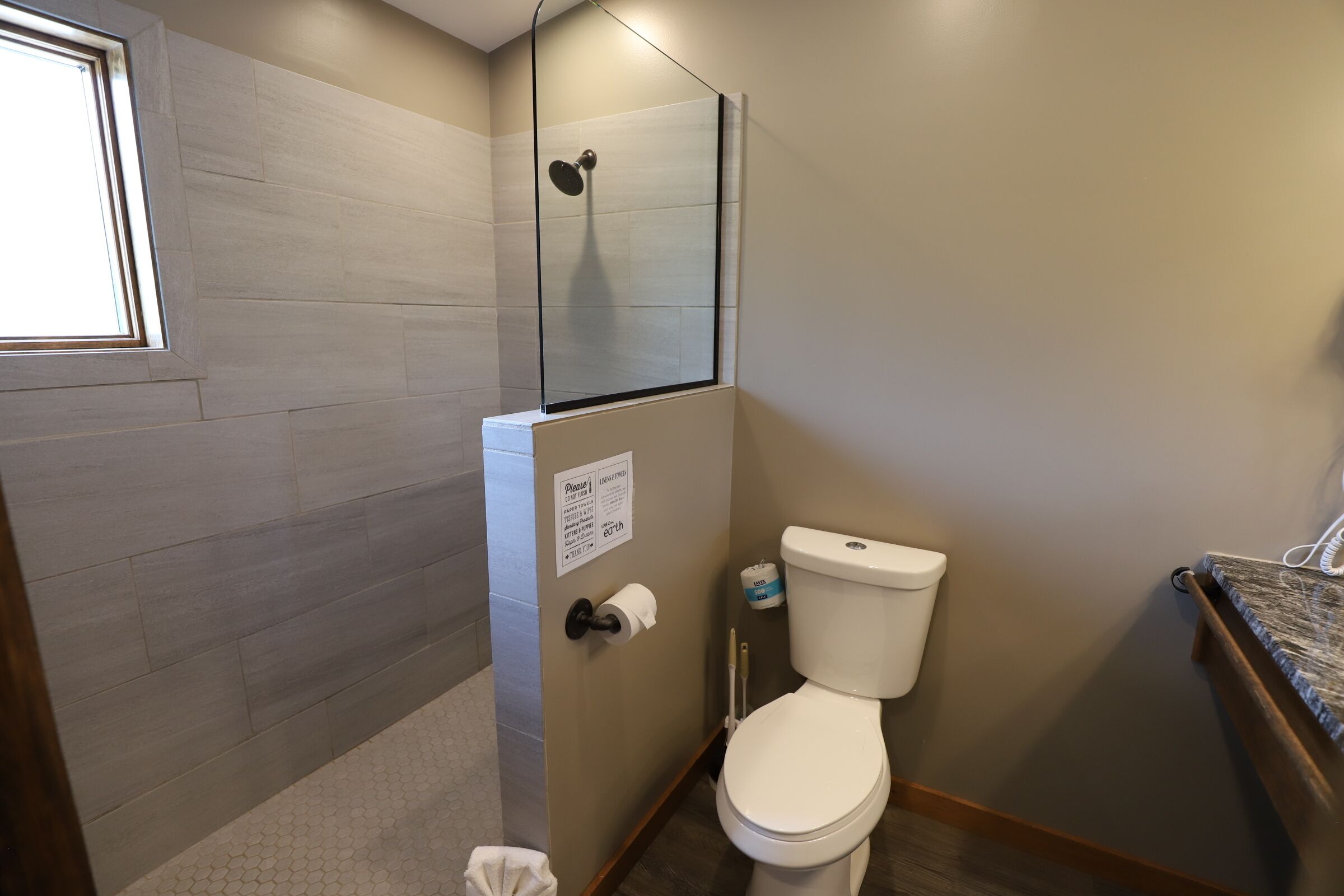 Un baño con ducha, inodoro y ventana.