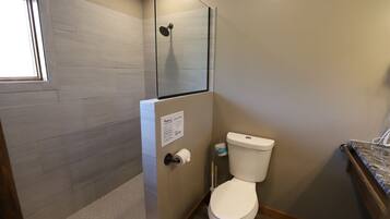Un baño con ducha, inodoro y ventana.
