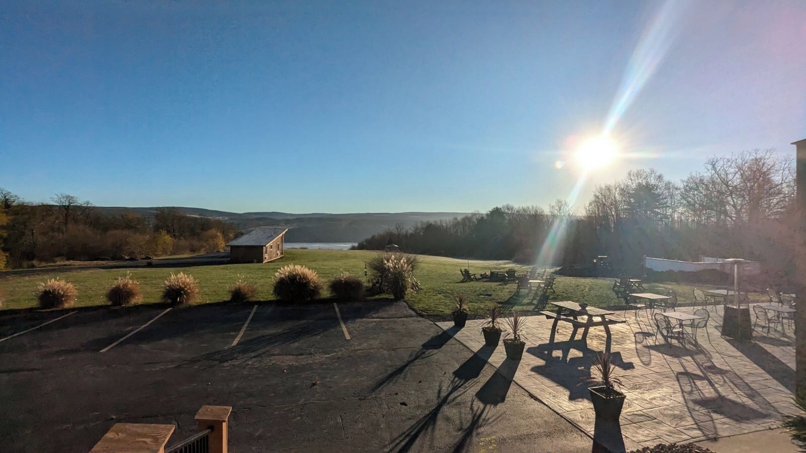 Un parking équipé de tables et de chaises pour pique-niquer, un petit bâtiment et une vue sur un lac.