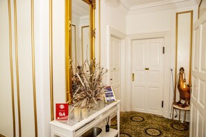 A hallway with a white console table, a large mirror, a decorative vase, and a sign indicating a 94% rating. - Godstedlund B&B (Oster Ulslev)