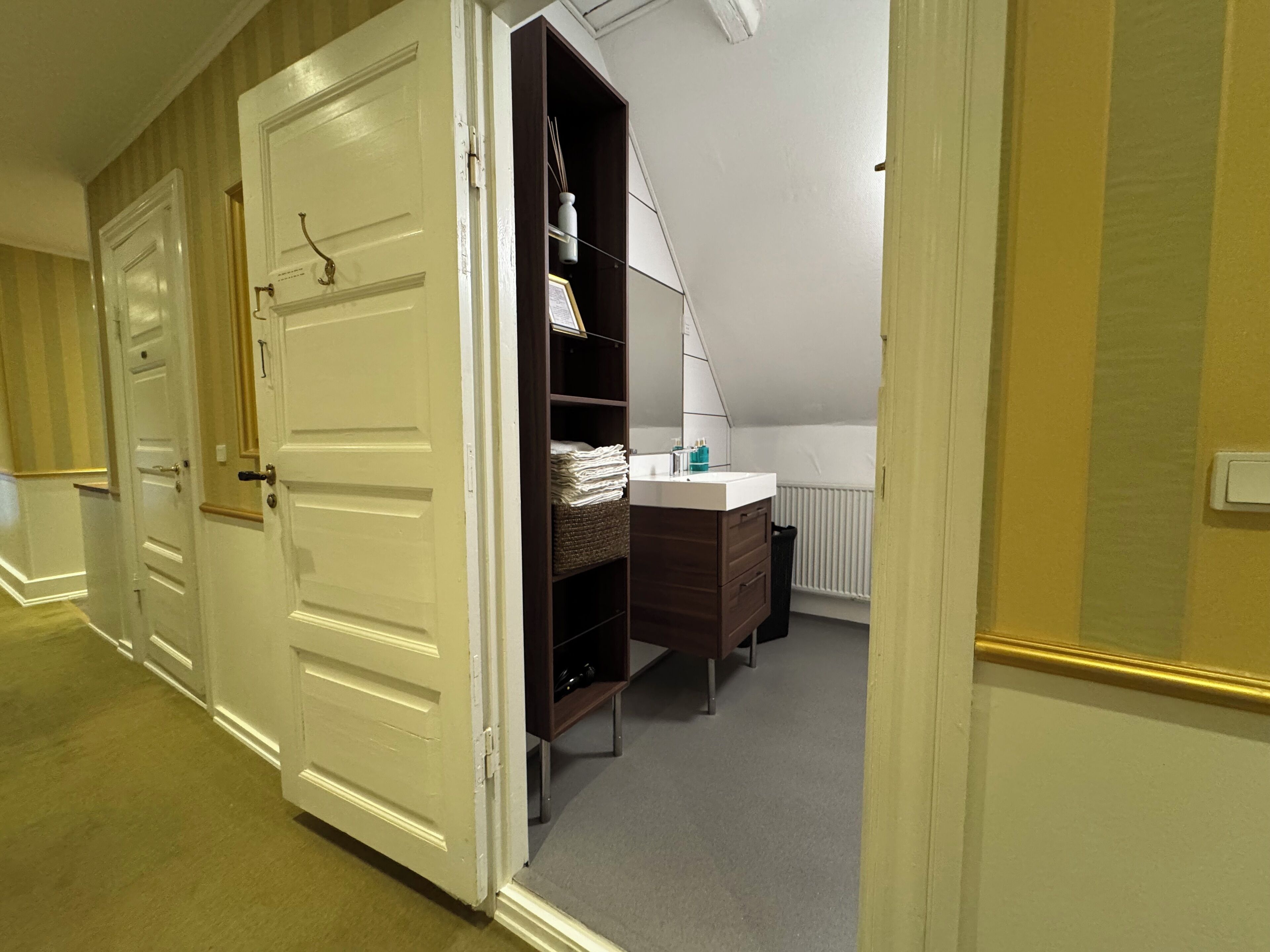 A hotel room with a walk-in closet, a vanity with a mirror, and a radiator.