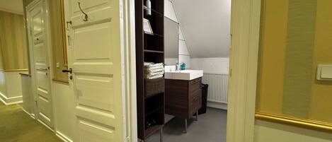 A hotel room with a walk-in closet, a vanity with a mirror, and a radiator.