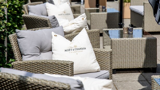 Wicker outdoor seating with cushions and a sign reading "MOËT & CHANDON CHAMPAGNE". - Godstedlund B&B (Oster Ulslev)
