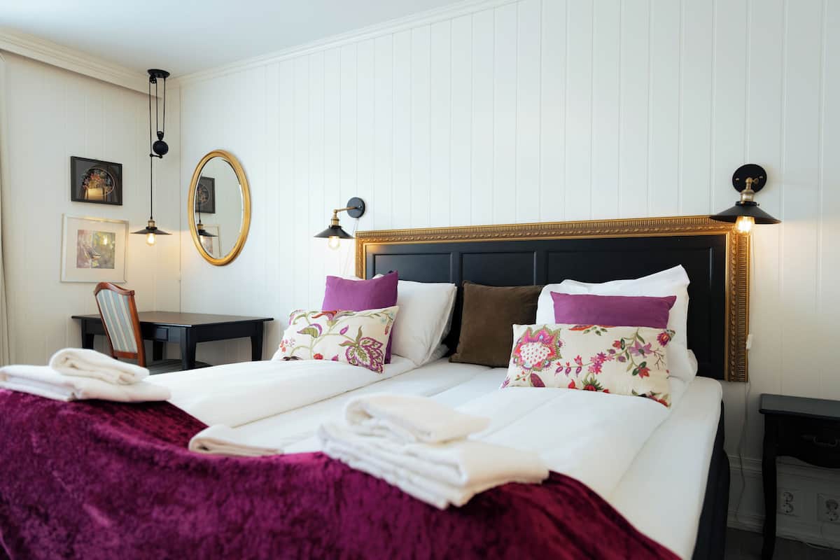 Een opgemaakt bed met hoofdbord, kussens en dekbed.