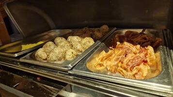 A buffet with meatballs, bacon, and other dishes.