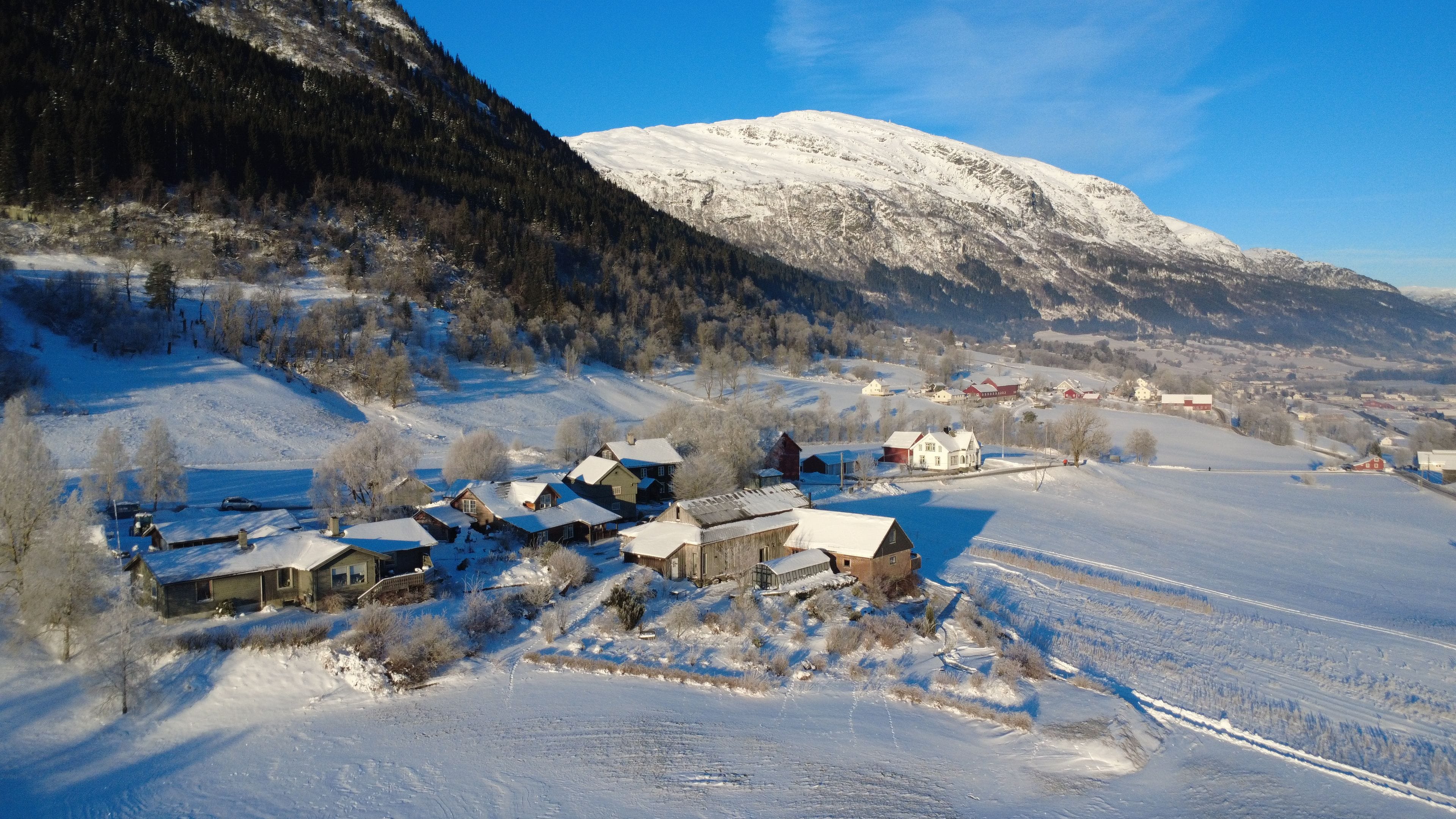 Un pueblo cubierto de nieve con casas y una montaña al fondo.
