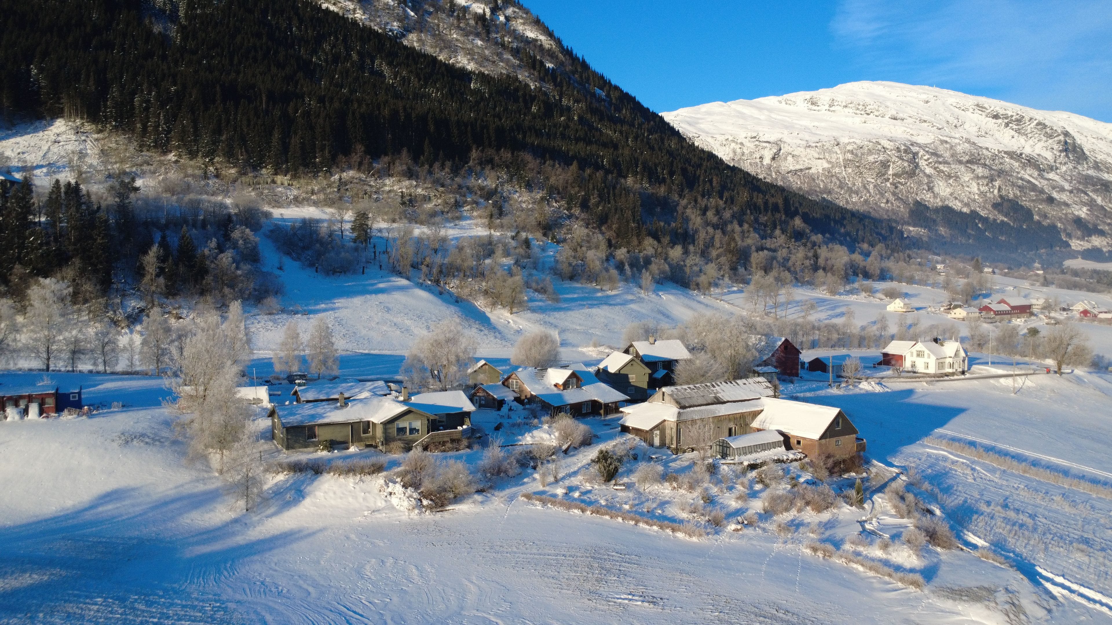 Un pueblo cubierto de nieve con casas y una montaña al fondo.