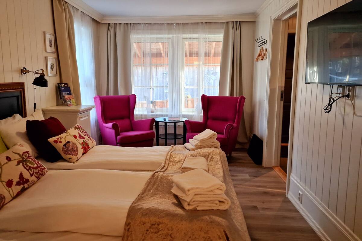 Een hotelkamer met twee bedden, een televisie, een tafeltje en een stoel.