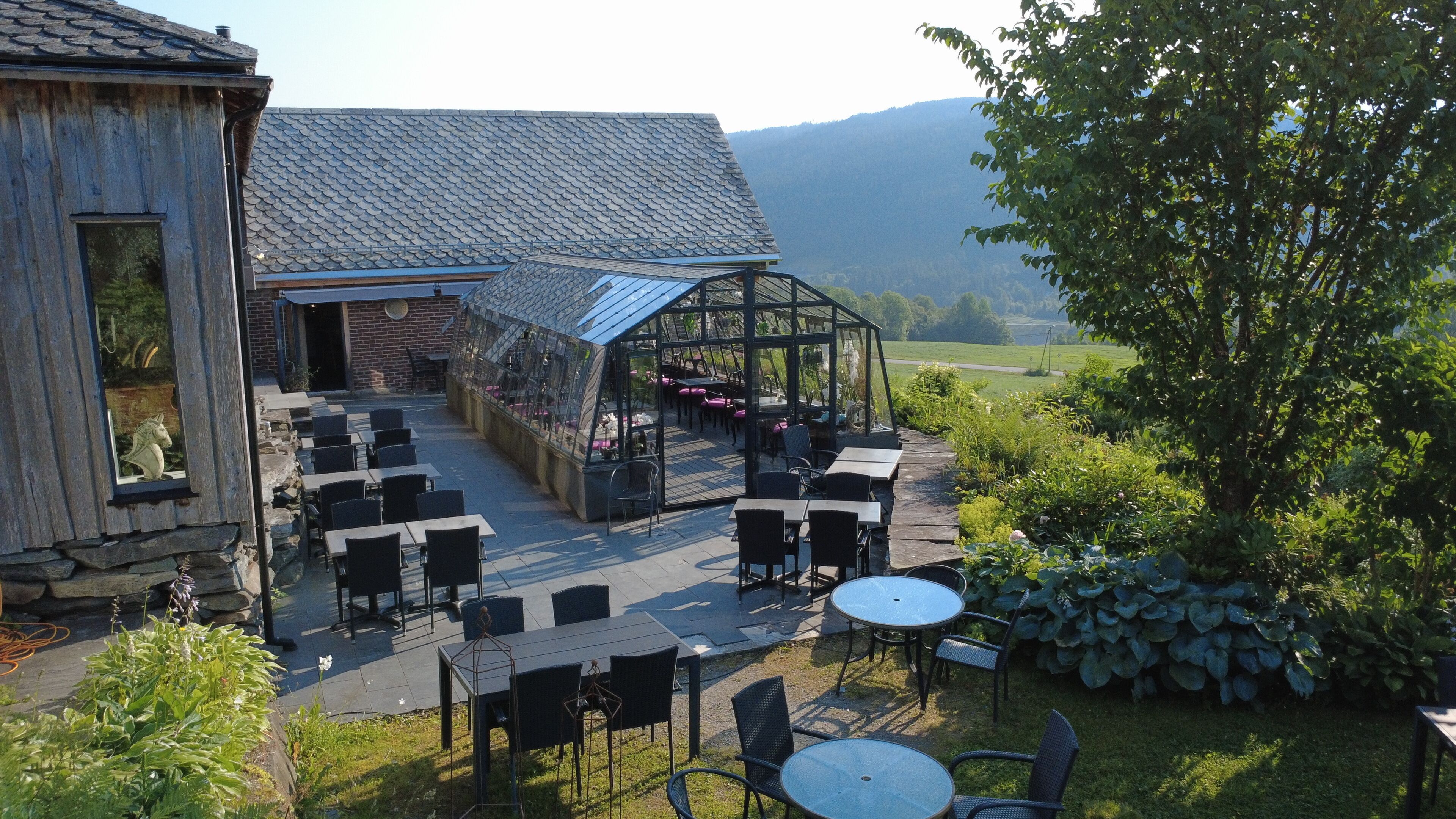 An outdoor seating area with tables and chairs, a covered patio, and a view of the surrounding landscape.
