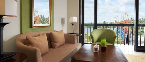 A modern living room with a sofa, a wooden coffee table, and a view of a colorful playground through large windows.