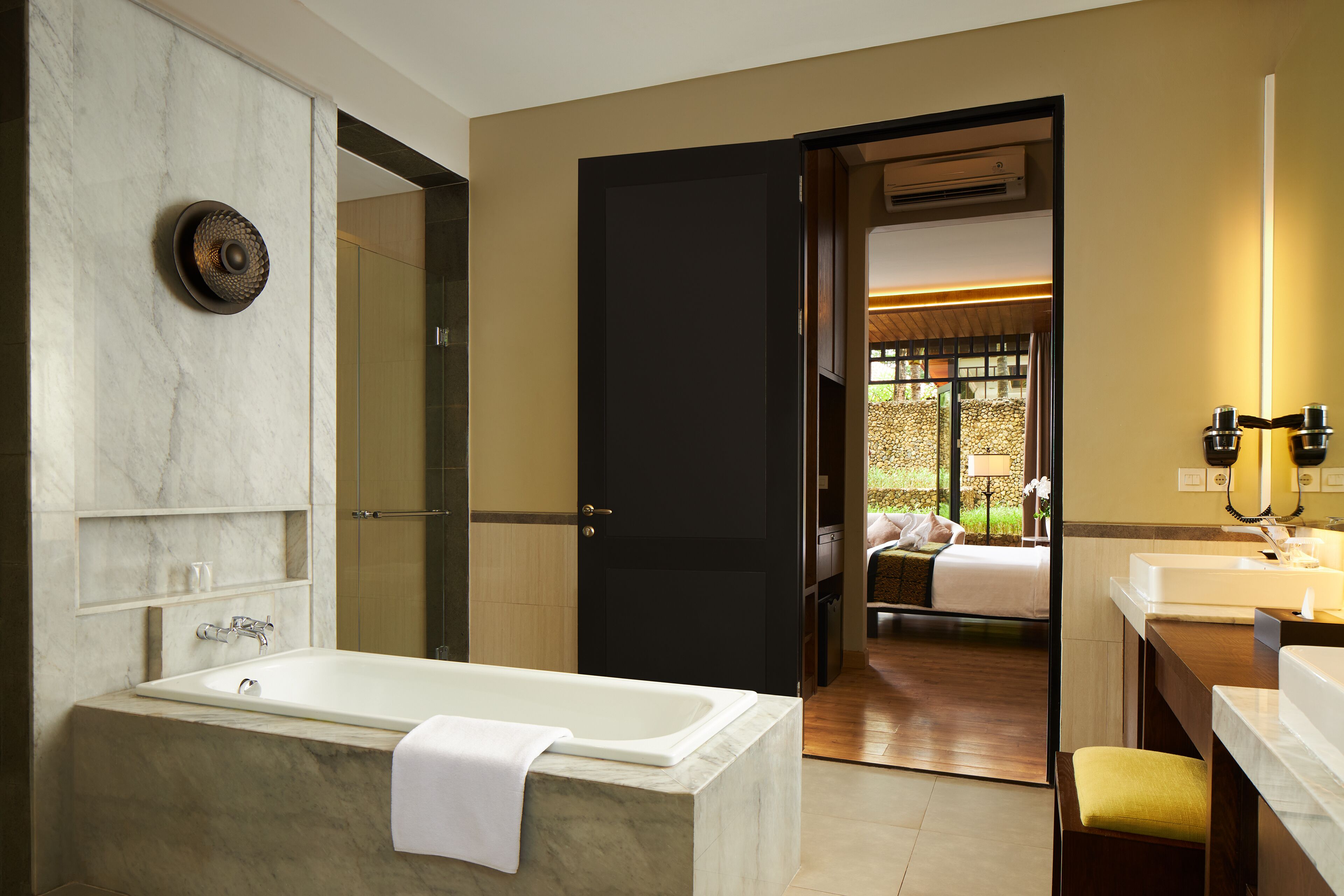 A modern bathroom with a marble bathtub, a separate shower area, and a vanity with a mirror.