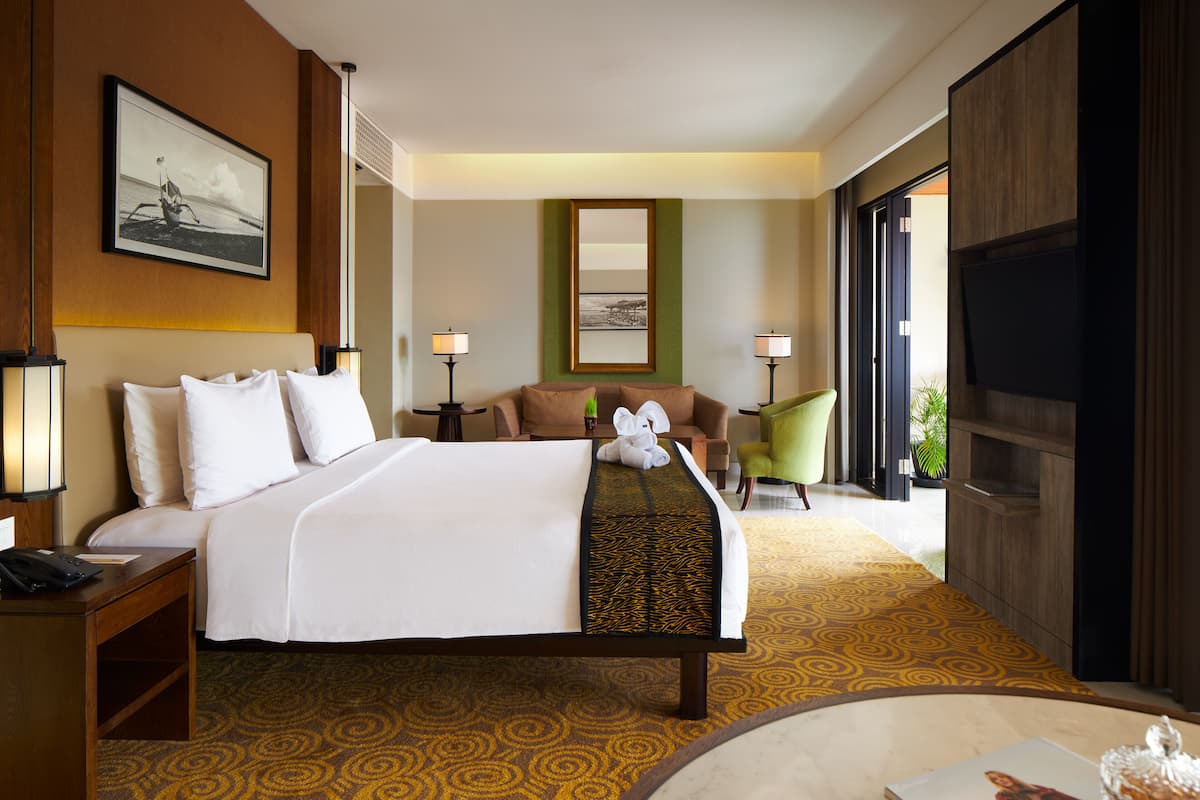 Habitación de hotel con una cama grande, un escritorio con teléfono, dos lámparas, un sofá y una silla.