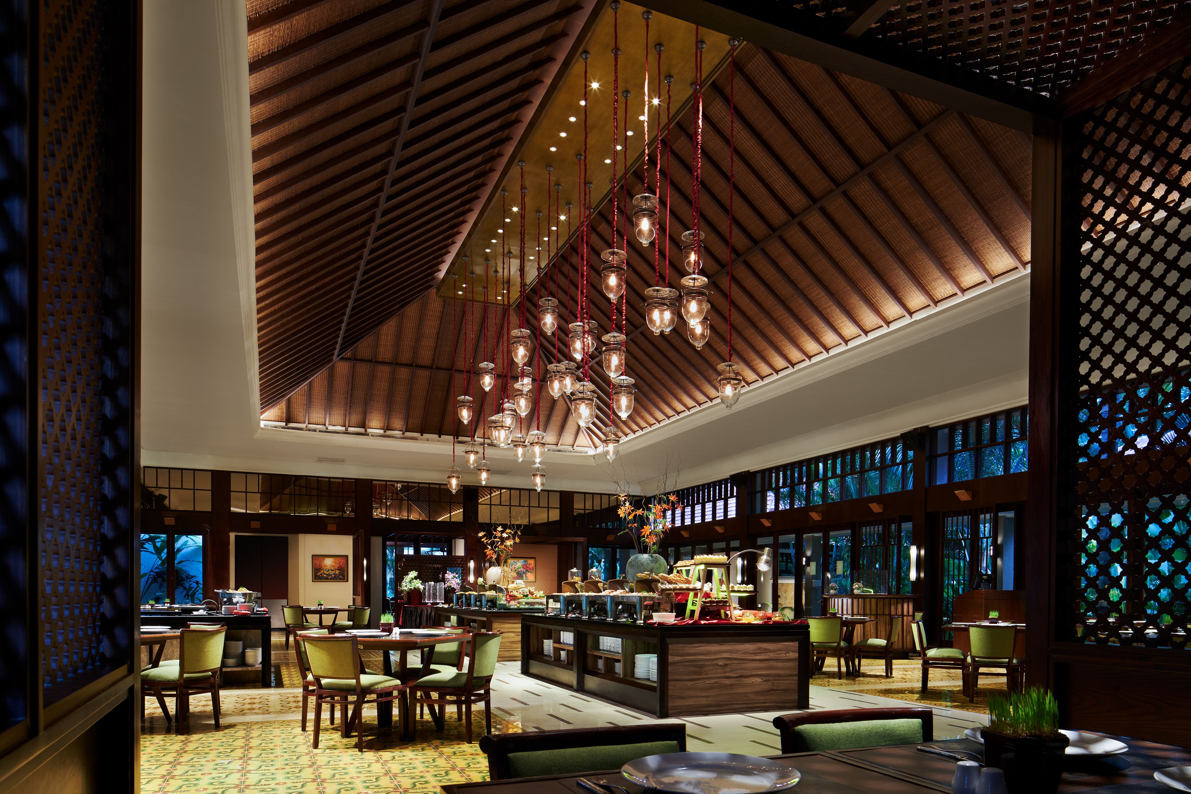 A spacious restaurant with high ceilings, hanging lights, and a central bar area.