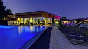 Une piscine avec des chaises longues et un bâtiment doté de grandes fenêtres.