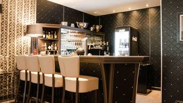 Een bar met een zwart-wit patroon op de muur, een koelkast en barstoelen.
