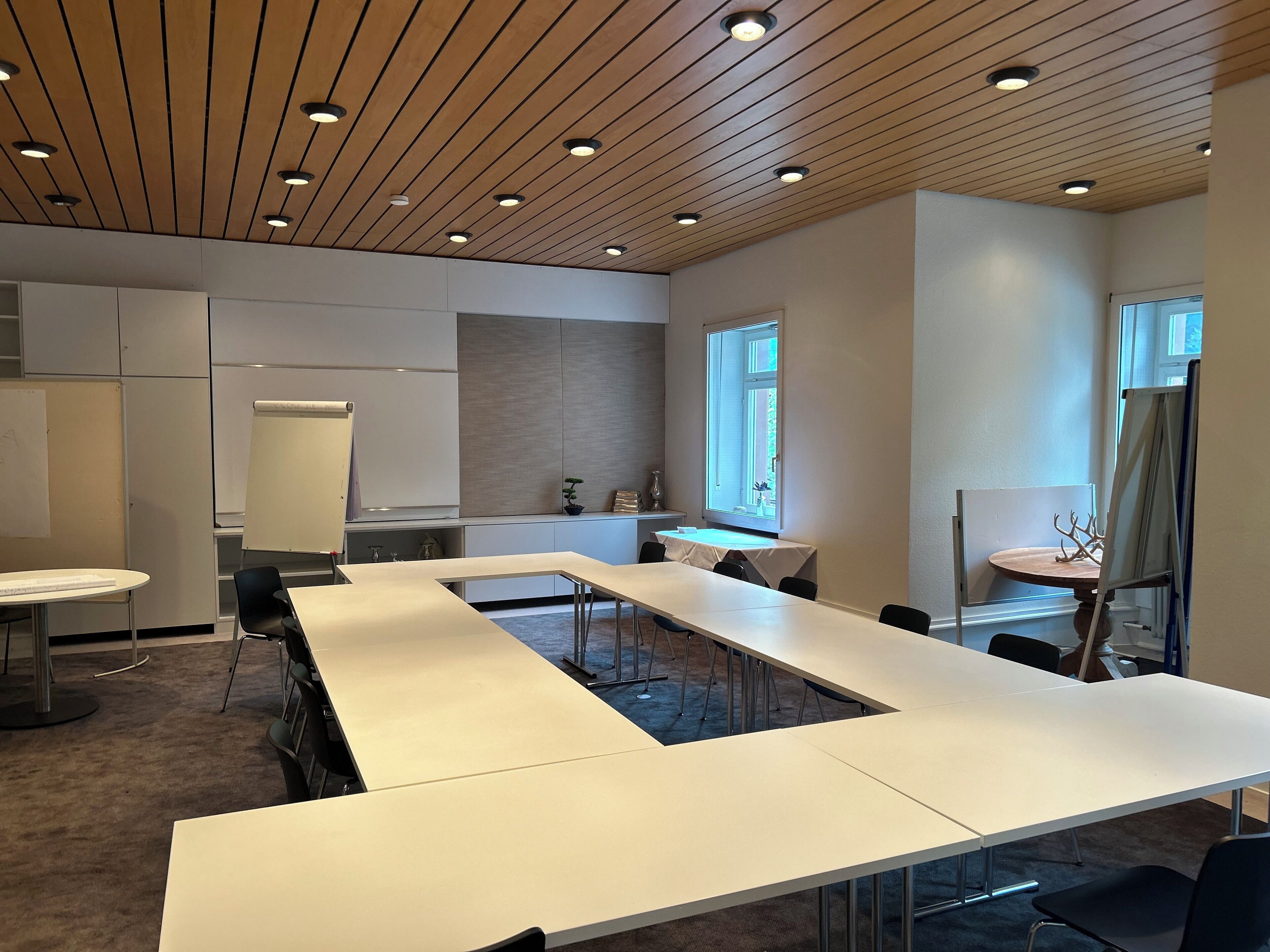 A conference room with long tables, whiteboard, and a large window.